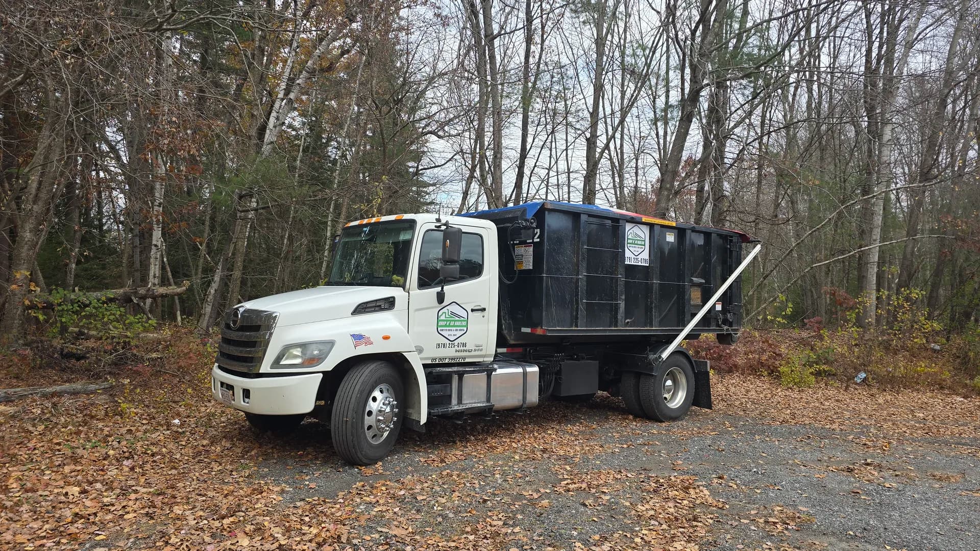 Truck with roll-off on a leaf-strewn fall driveway